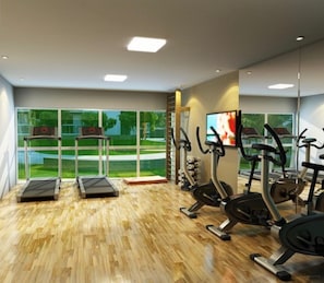 Ein Fitnessraum mit Laufbändern, Crosstrainern und einem Fernsehbildschirm.