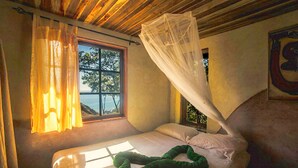 A bed with a canopy, a window with curtains, and a view of the outdoors. - Montezuma Heights "Geco" studio. In between ocean and the wild. Sleeps 2 (Montezuma)