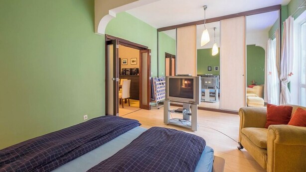 Ett hotellrum med två sängar, en TV, en soffa och ett stort fönster.