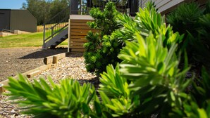A landscaped garden area with a wooden deck, a staircase, and various green plants. - High View Accommodations # 3 (Freemans Reach)