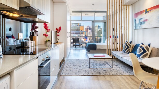 Un apartamento moderno con cocina, comedor y sala de estar con vista a la ciudad.