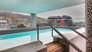 Una piscina interior con vistas a un paisaje urbano, que incluye edificios y colinas.