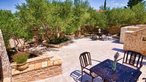 Une terrasse extérieure avec un sol en pierre, des plantes en pot et du mobilier en métal.