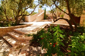 Step up to a tranquil retreat surrounded by lush greenery and a rustic stone wall.
