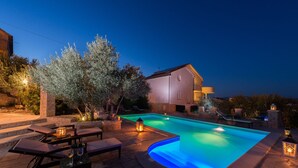 Une piscine à bord incurvé, entourée de marches en pierre et de mobilier d’extérieur.