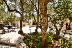 Relax in a tranquil outdoor space surrounded by lush trees and shrubs, perfect for dining or socializing.