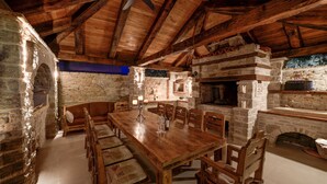Une cheminée en pierre rustique, une table à manger en bois et des bancs.