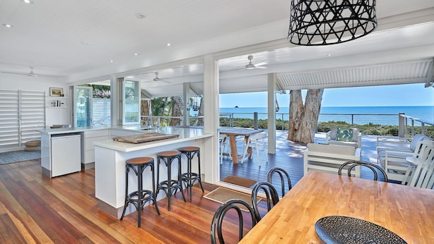Una cocina espaciosa con una isla grande, suelo de madera y vista al océano.