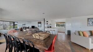 Un amplio salón con una mesa de comedor de madera, sillas rojas y un sofá gris.