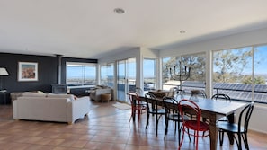 A spacious living area with a large dining table, comfortable seating, and a view of the outdoors.