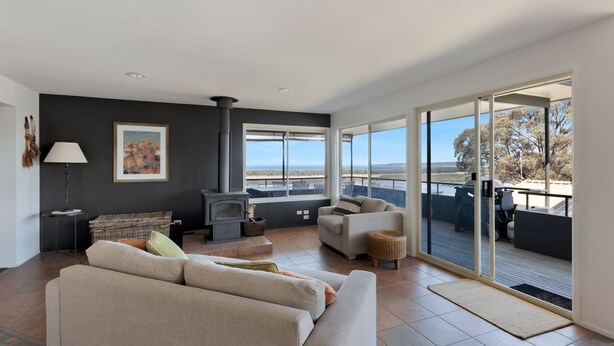 Una sala de estar moderna con chimenea, un sofá, un sillón y vistas al exterior.
