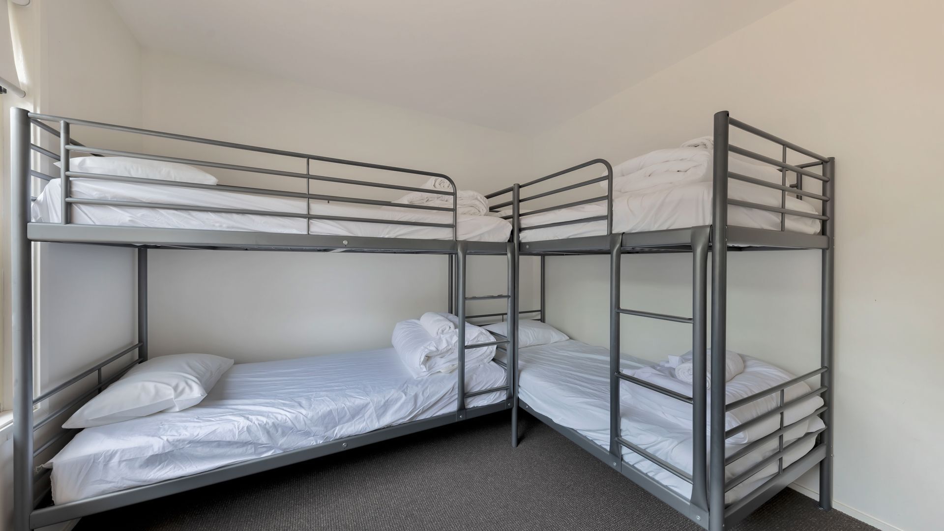 A bunk bed room with metal railings and white bedding.