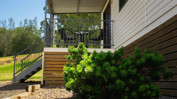A covered outdoor area with a wooden deck, metal railing, and a table with chairs.