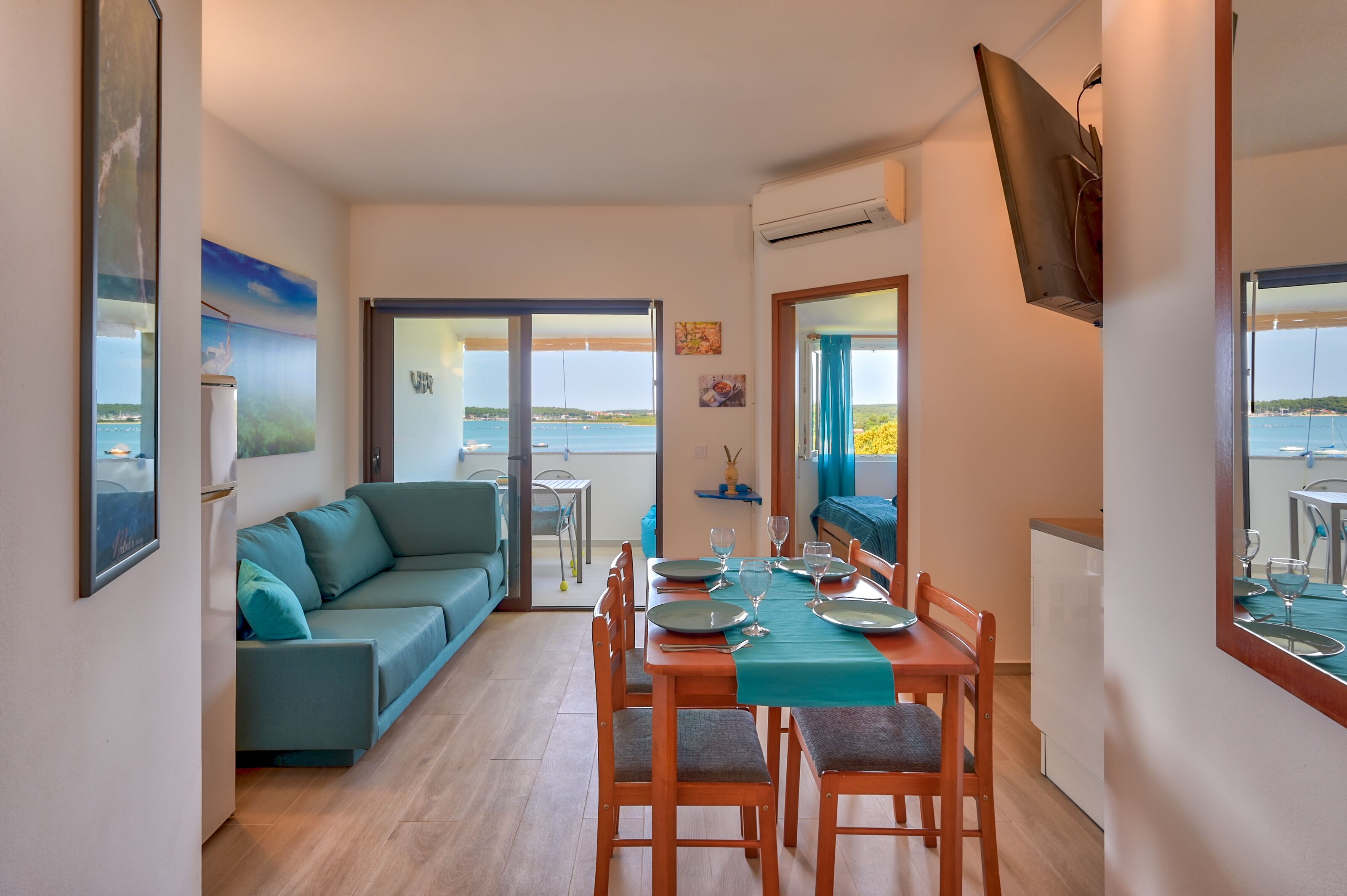 A dining area with a table set for four, a sofa, and a view of the sea.