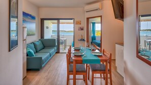 Een eetgedeelte met een tafel voor vier personen, een bank en uitzicht op zee.