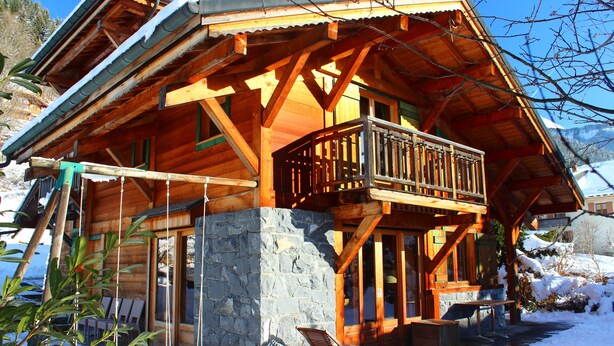 Eine Holzhütte mit Balkon, Stein Fundament und einer Holzterrasse.