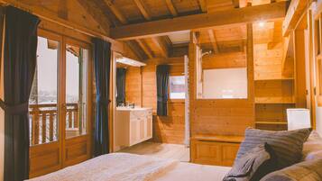 Une chambre dans une cabane en bois, avec un lit, une petite table de chevet et une fenêtre avec des rideaux.