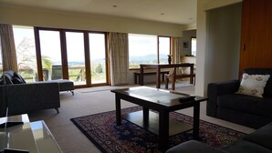 A spacious living room with a large window, a dining area, and a sofa.