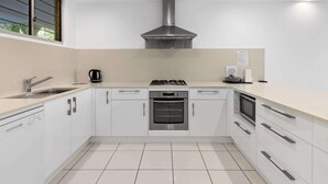 Uma cozinha moderna com armários brancos, eletrodomésticos de aço inoxidável, fogão a gás, forno e micro-ondas.