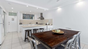 Uma cozinha moderna com armários brancos, uma mesa de jantar de madeira e um ventilador de teto.