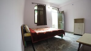 Een slaapkamer met een bed, een bureau, een kledingkast en een raam met gordijnen.