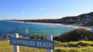 A sign for Lighthouse Beach with a view of the beach and ocean.