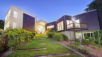 A modern two-story house with a well-maintained lawn and a wooden fence with the number 34.