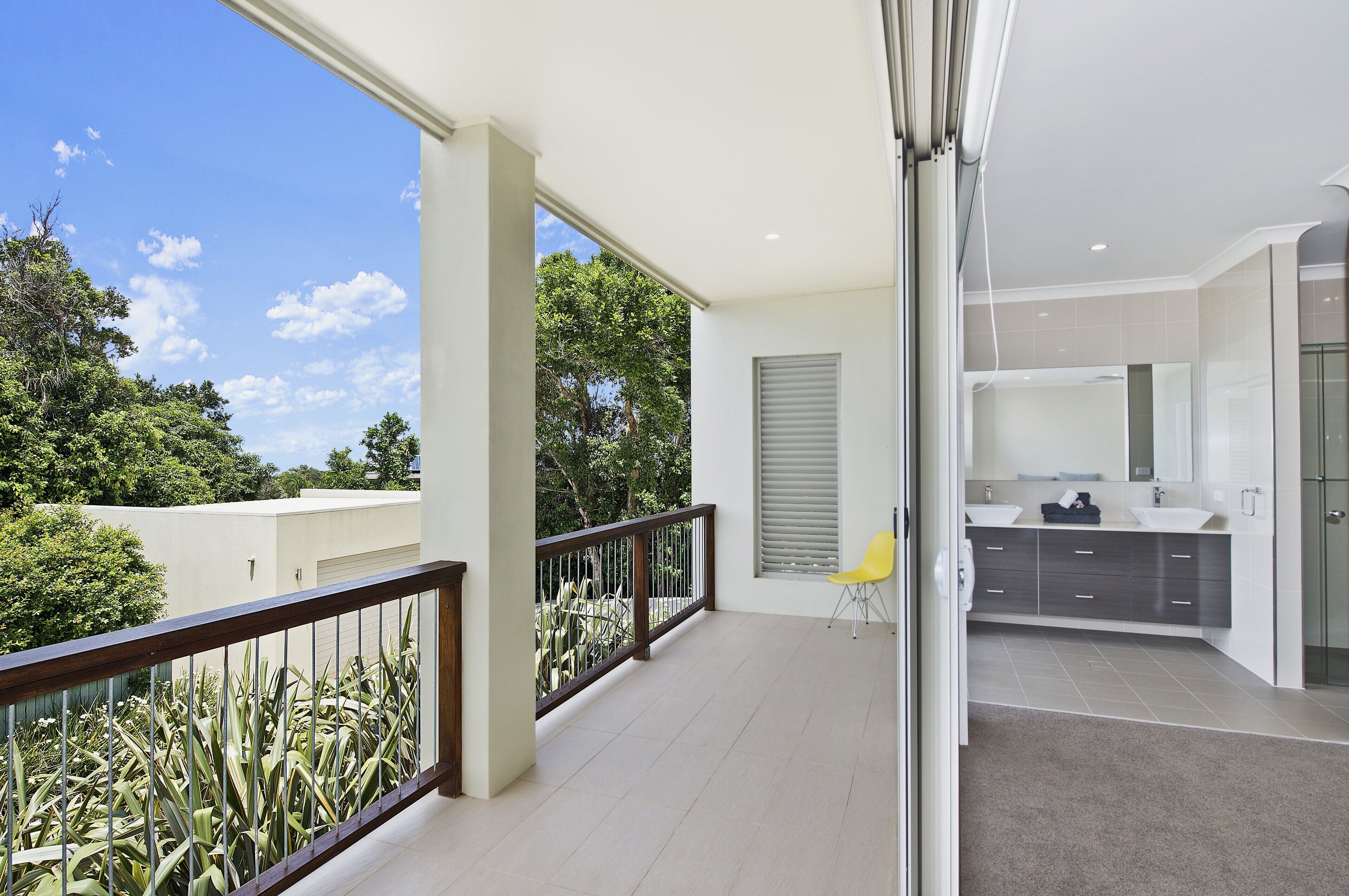 A modern apartment with a balcony, a kitchen with a large window, and a view of greenery.