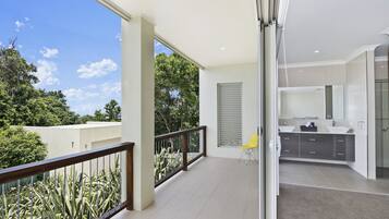 A modern apartment with a balcony, a kitchen with a large window, and a view of greenery.