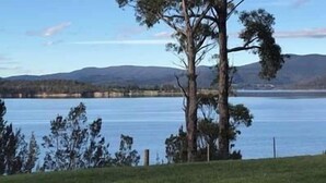 Un lac bordé d’arbres, avec des montagnes en arrière-plan.