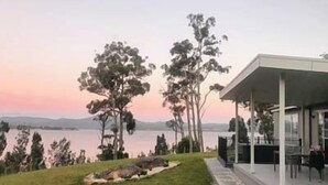 Une maison moderne dotée d’un patio couvert donnant sur un lac.