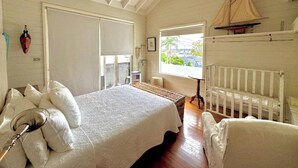 A bedroom with a bed, a crib, a sailboat model, a window with a view, and a ceiling fan. - The Abode - 2-3 bedrooms - premium, spacious, light-filled and harbour views (Birchgrove)