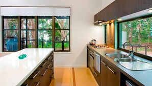 A modern kitchen with a large window, wooden cabinets, and stainless steel appliances.