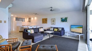 A modern living room with a sofa set, a coffee table, and a television. - Frangipani Lodge 008, Beachfront Apartment on Hamilton Island (Hamilton Island)