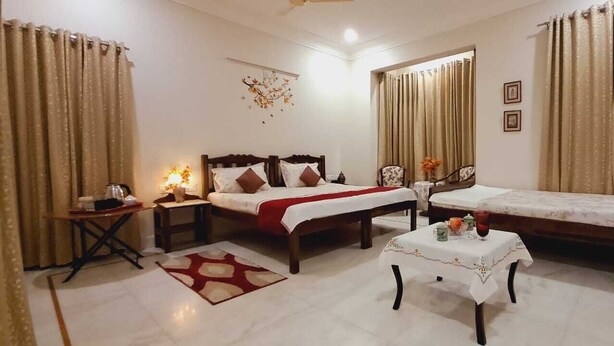 A hotel room with two beds, a small table, a nightstand, and curtains. - Colonels Home stay - A home away from home. Set in a scenic natural environment. (Sector 14)
