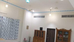 A spacious room with a marble floor, a ceiling fan, and a large cabinet with glass doors. - Colonels Home stay - A home away from home. Set in a scenic natural environment. (Sector 14)