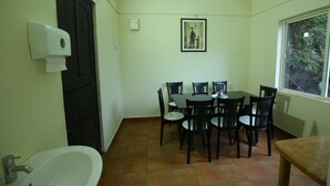 Une petite pièce propre, équipée d’un lavabo, d’une table avec des chaises, d’une fenêtre et d’une porte.