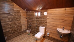 Une salle de bain avec un plancher en bois, des toilettes, un lavabo et une douche.