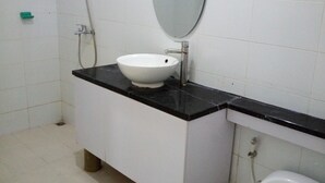 Un baño con un lavabo blanco, encimera negra y un inodoro blanco.