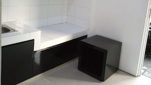 Una cocina moderna con azulejos blancos, armarios negros y un taburete negro pequeño.