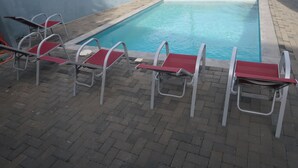 A swimming pool with red chairs and metal ladders. - Apartment ground floor B (Willemstad)