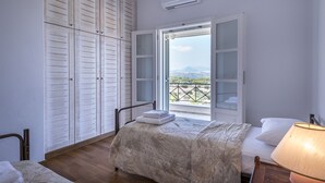 Une chambre à coucher comprenant un lit, une table de chevet, une fenêtre avec vue et une armoire.