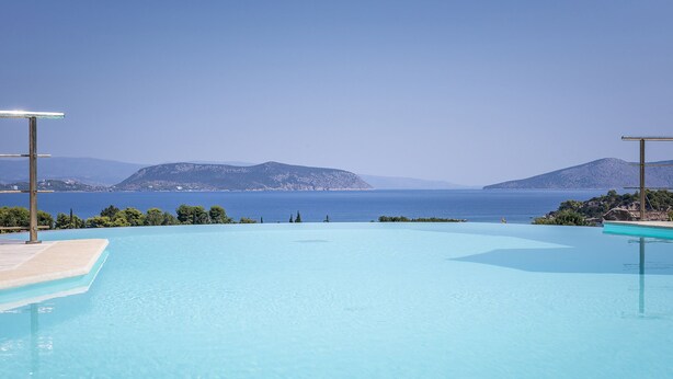Une piscine d’eau cristalline offrant une vue sur la mer et les montagnes.