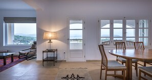 A dining area with a table, chairs, a lamp, and a view of the outdoors.