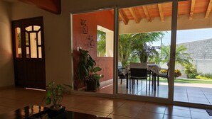 A spacious room with a sliding glass door leading to an outdoor patio. There is a wooden table with a plant on it, and a potted plant against the wall.