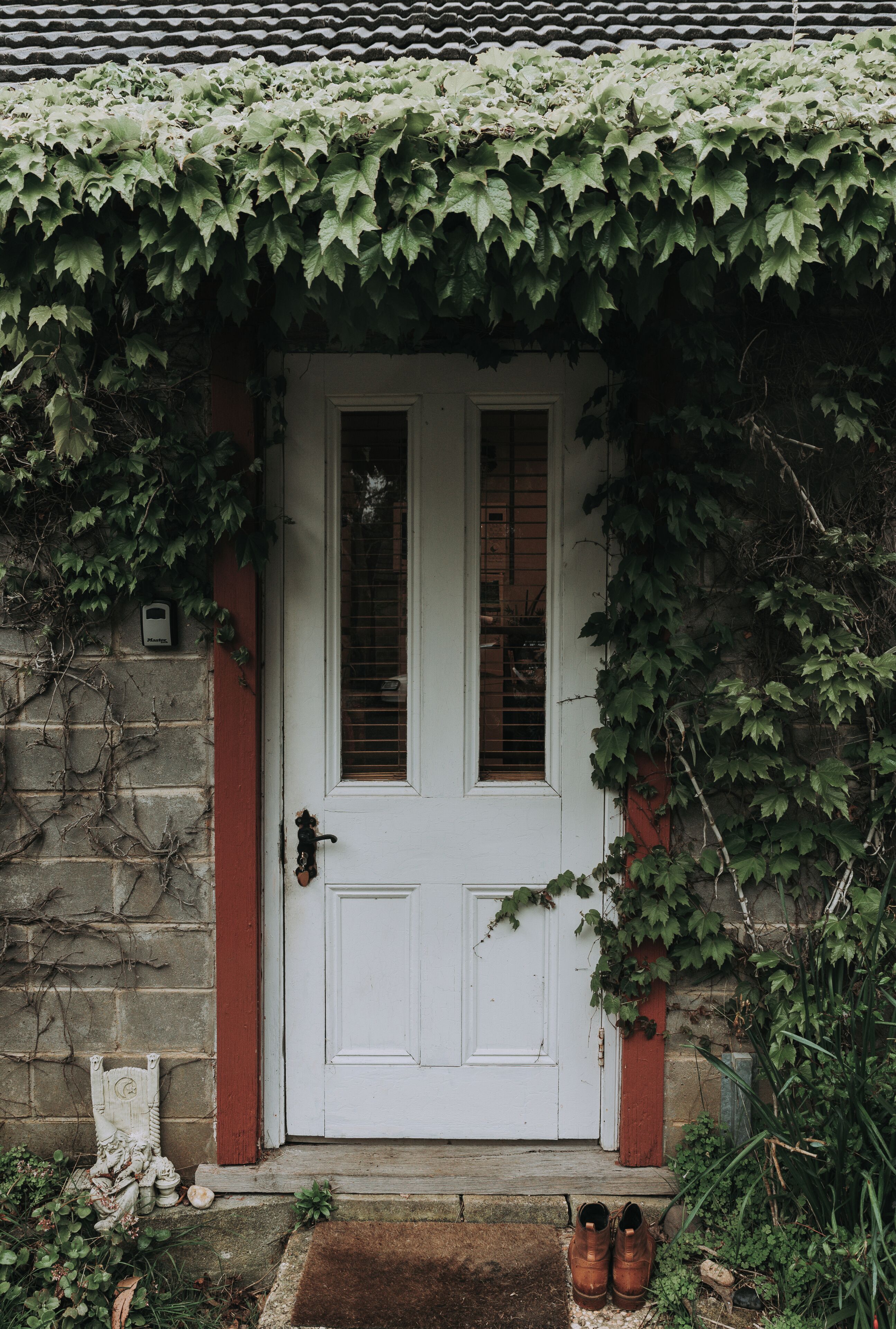 Une porte blanche avec une petite fenêtre, entourée de lierre.
