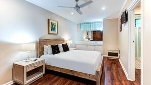 Ein Schlafzimmer mit einem hölzernen Bett, Nachttisch und Deckenventilator.