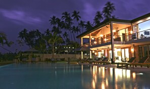 A two-story resort with a swimming pool, outdoor seating, and a view of palm trees at night. - The Lookout Sri Lanka Luxury Beachfront Villa (Dikwella nr Hirikatiya) (Dikwella)