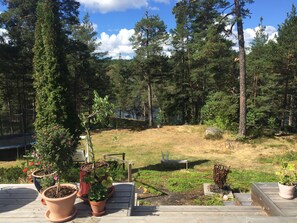 Relax on the deck with a bench and table, surrounded by lush greenery and a serene forest view.