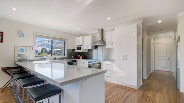 Una cocina moderna con una isla central, electrodomésticos de acero inoxidable y suelo de madera.